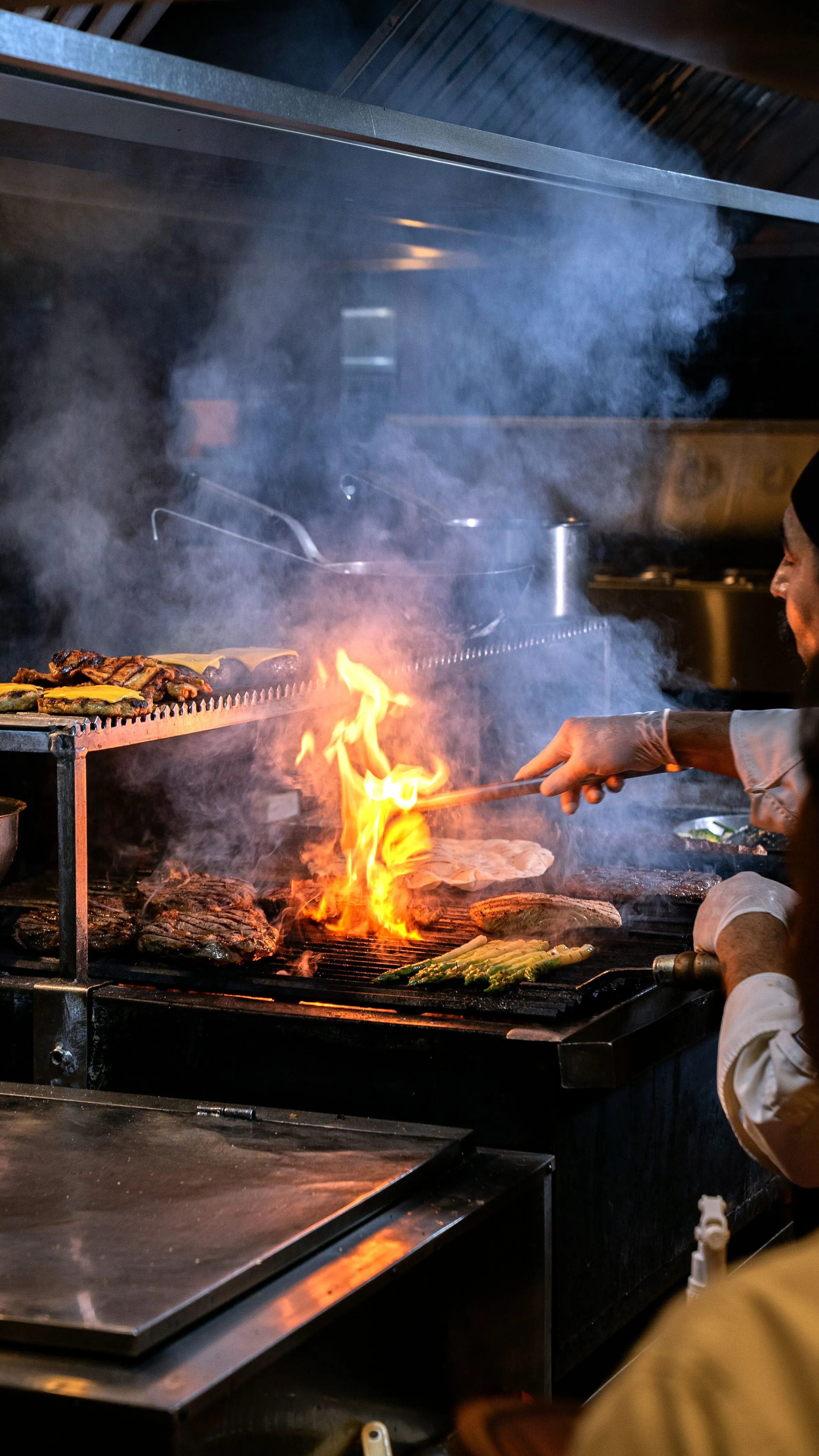Cocina de brasa abierta de Asador Artebe con llamas y humo mientras se asa el pescado